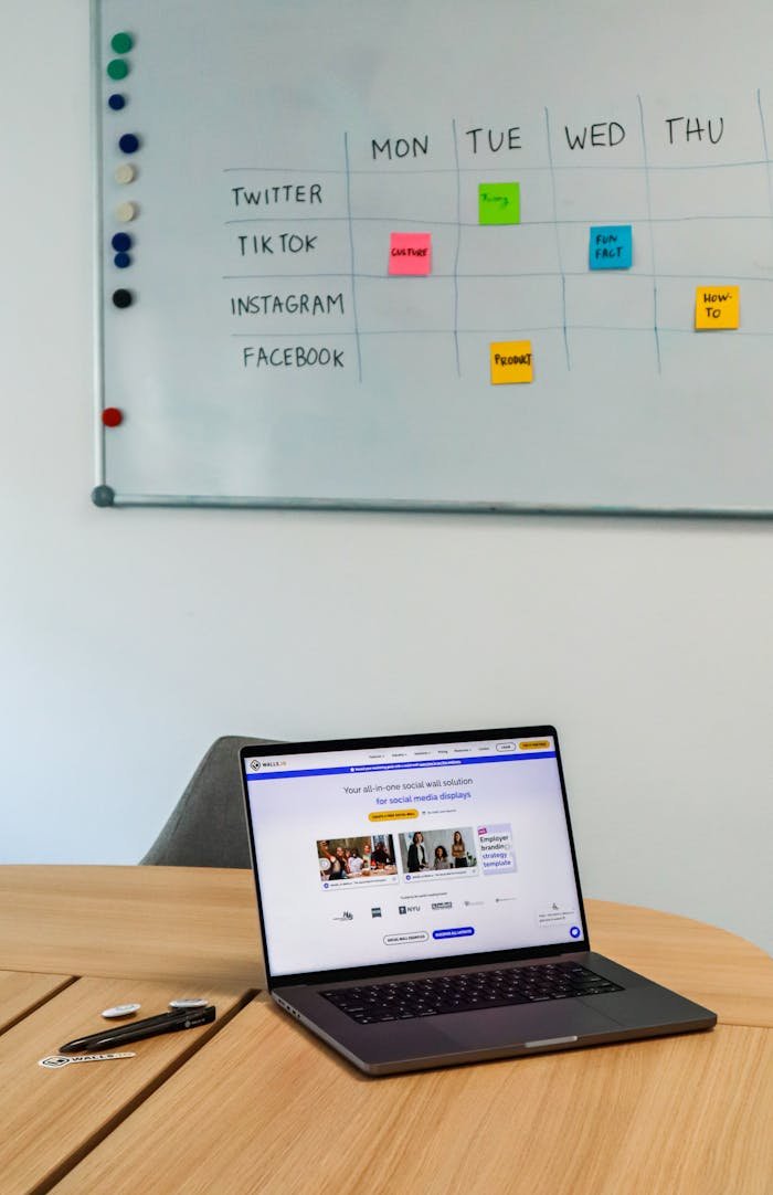 services-02 A modern office setup featuring a laptop and a whiteboard schedule for social media platforms.